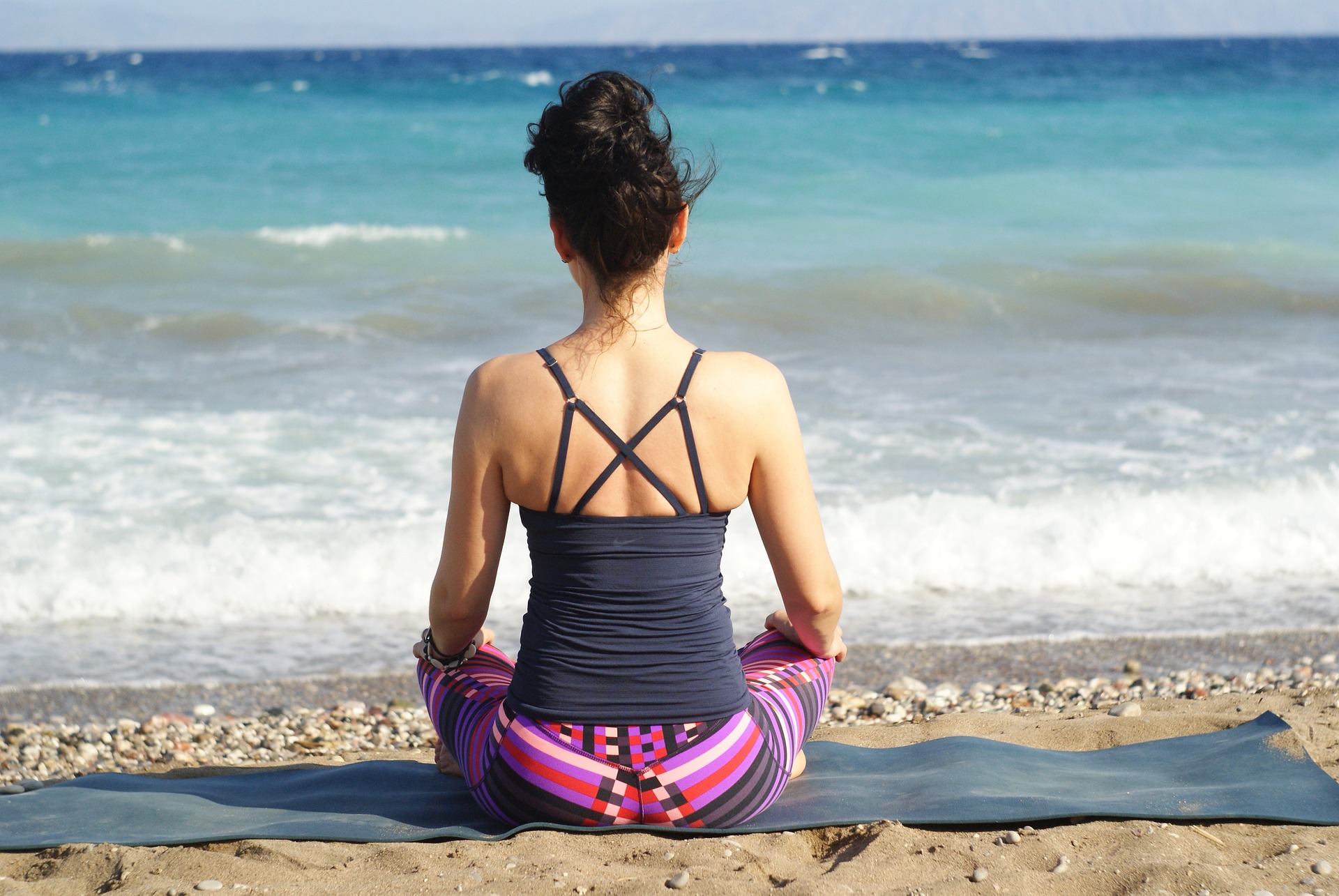 woman sitting cross-legged on the beach